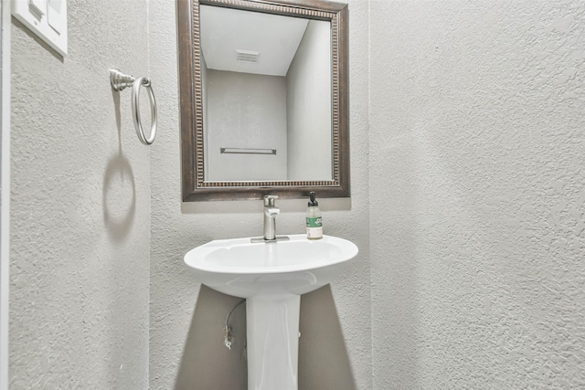 bathroom featuring a textured wall and visible vents