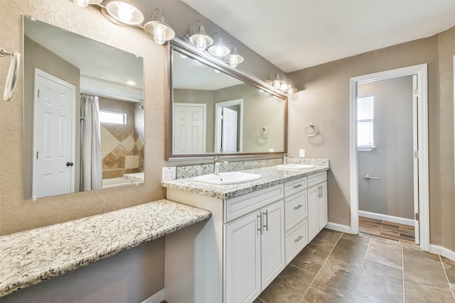 bathroom featuring baseboards, a sink, and double vanity