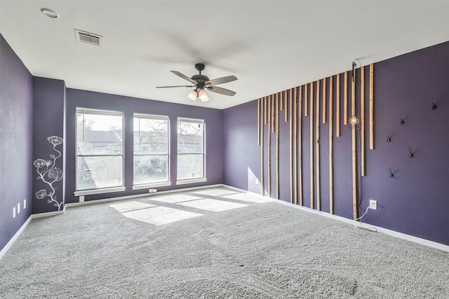 carpeted spare room featuring baseboards, a ceiling fan, and visible vents
