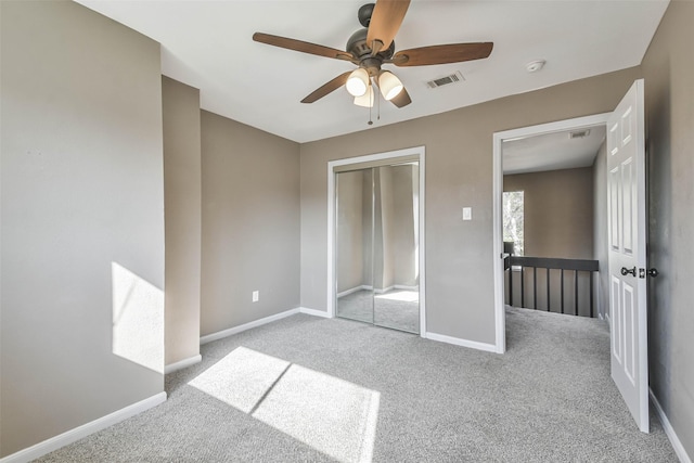 unfurnished bedroom with carpet flooring, baseboards, visible vents, a ceiling fan, and a closet