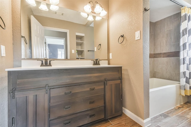 bathroom featuring double vanity, a textured wall, baseboards, and a sink