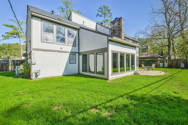 back of house with a yard, a patio area, a chimney, and a fenced backyard
