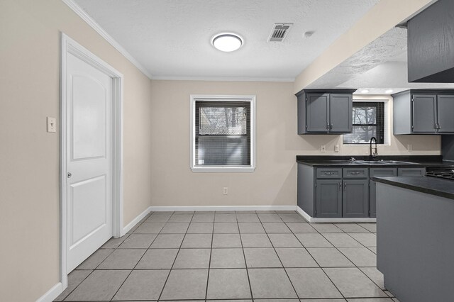 kitchen with dark countertops, gray cabinets, baseboards, visible vents, and crown molding
