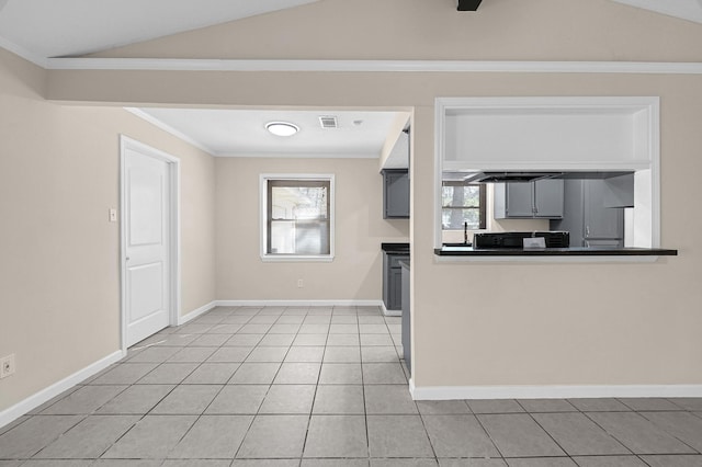 kitchen featuring light tile patterned flooring, dark countertops, baseboards, and crown molding