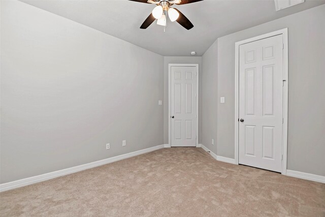 unfurnished bedroom featuring baseboards, light colored carpet, ceiling fan, and visible vents