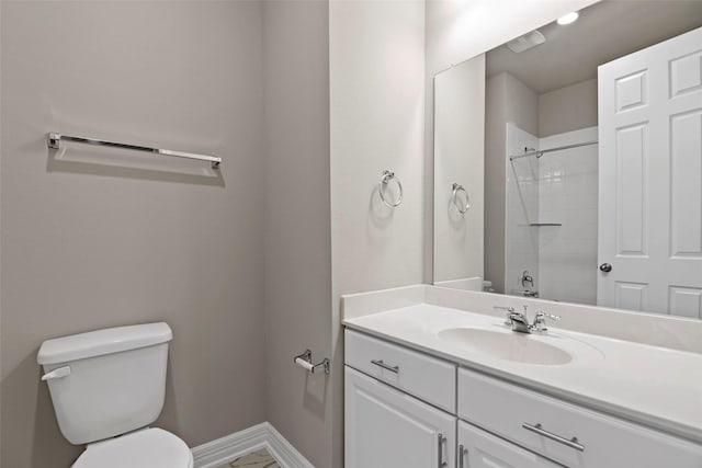 bathroom featuring toilet, baseboards, a shower, and vanity