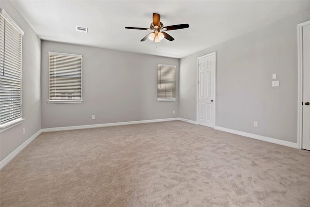 unfurnished bedroom featuring baseboards, multiple windows, light carpet, and visible vents
