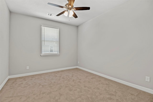 carpeted spare room with visible vents, a ceiling fan, and baseboards