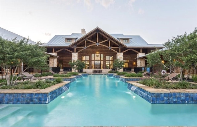 back of property with a chimney, metal roof, and an outdoor pool