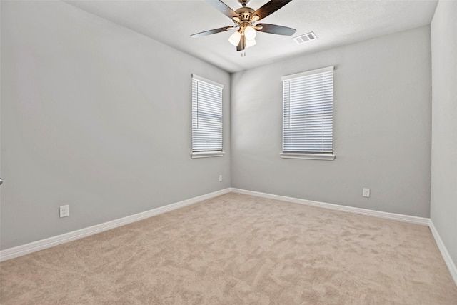 empty room featuring visible vents, baseboards, ceiling fan, and carpet floors