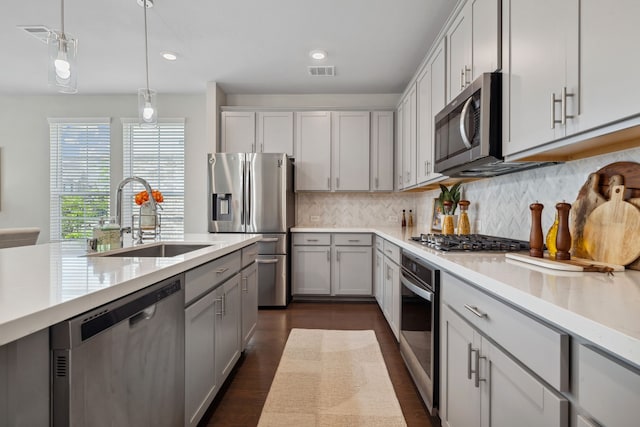 kitchen featuring appliances with stainless steel finishes, a sink, light countertops, dark wood finished floors, and visible vents