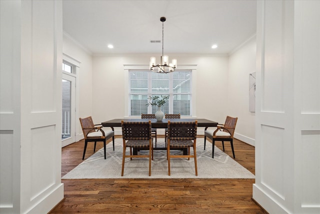 dining space with a chandelier, wood finished floors, visible vents, and crown molding