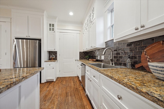 kitchen featuring wood finished floors, a sink, glass insert cabinets, appliances with stainless steel finishes, and white cabinetry