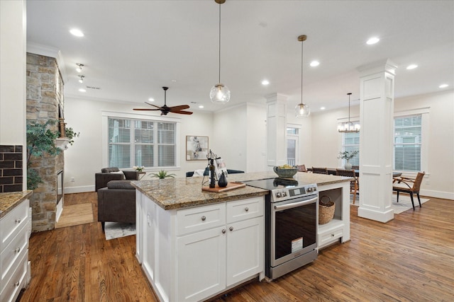 kitchen with stainless steel electric range, open floor plan, white cabinets, dark wood-style floors, and ornate columns