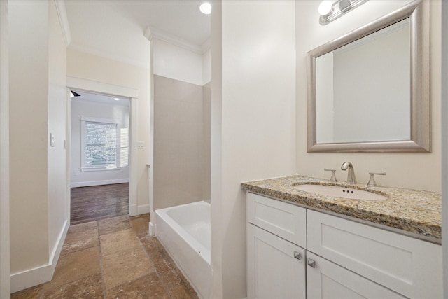 bathroom featuring baseboards, stone tile flooring, vanity, and crown molding