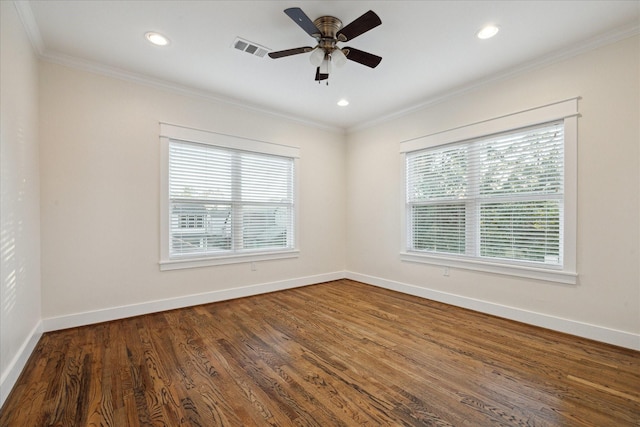 empty room featuring dark wood-type flooring, visible vents, baseboards, and ornamental molding