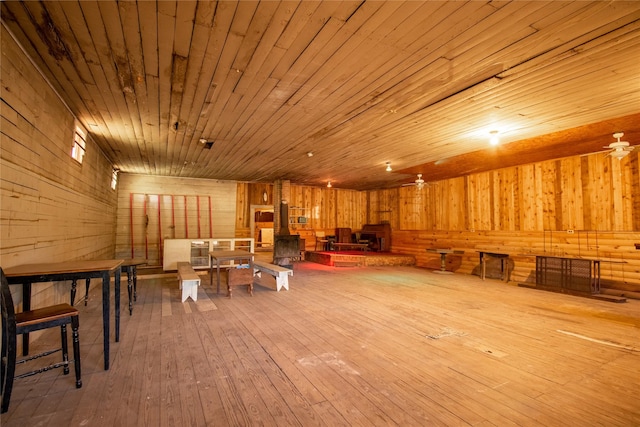 interior space with wooden walls, hardwood / wood-style flooring, a wood stove, and wooden ceiling