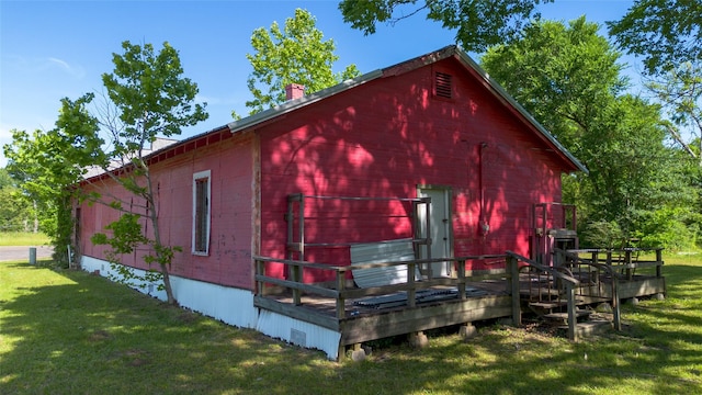 exterior space featuring a lawn, a deck, a barn, and a chimney