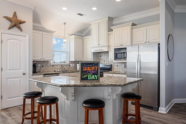 kitchen featuring stainless steel appliances, wood finished floors, visible vents, and a breakfast bar