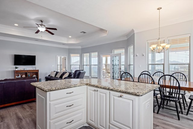 kitchen featuring light wood finished floors, visible vents, white cabinetry, ceiling fan with notable chandelier, and a raised ceiling
