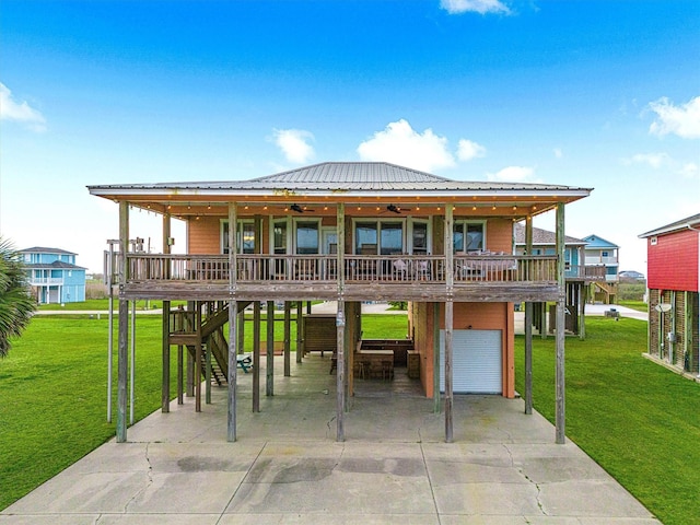back of house featuring stairway, a ceiling fan, a yard, concrete driveway, and a carport