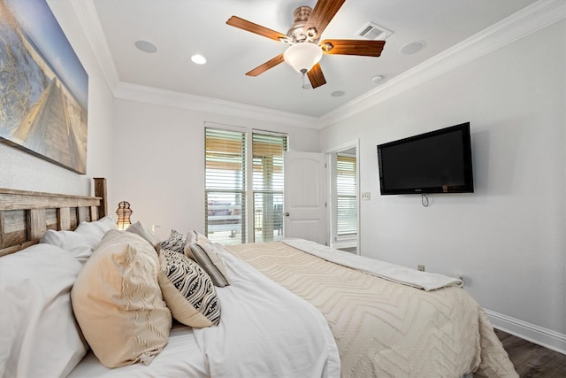bedroom featuring visible vents, baseboards, wood finished floors, and crown molding