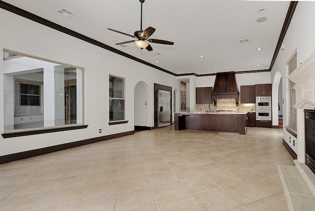 kitchen with visible vents, arched walkways, premium range hood, and light countertops