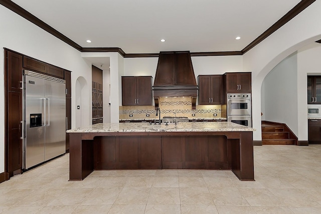 kitchen with crown molding, a sink, premium range hood, stainless steel appliances, and backsplash