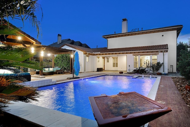 pool at night featuring a patio area, an outdoor pool, and an outdoor hangout area