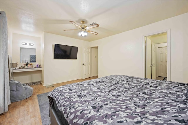 bedroom featuring light wood-style floors, ceiling fan, ensuite bath, visible vents, and baseboards