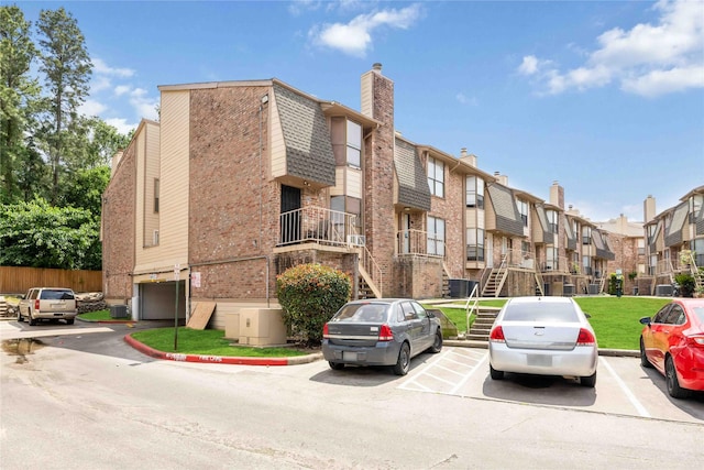 view of building exterior featuring a residential view, uncovered parking, and stairs