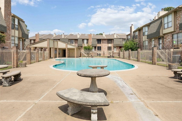community pool with fence, a patio area, and a residential view