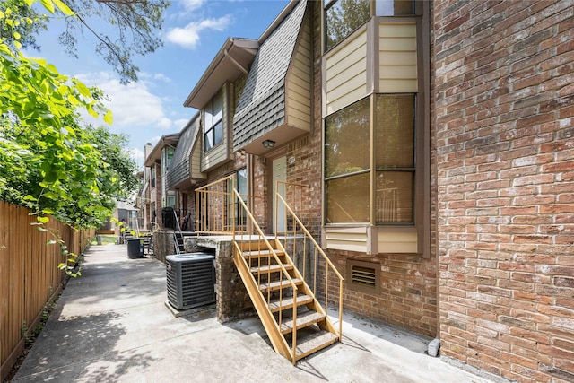 view of home's exterior with brick siding, fence, and cooling unit