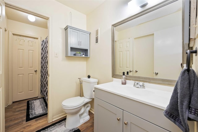 bathroom with visible vents, baseboards, toilet, wood finished floors, and vanity