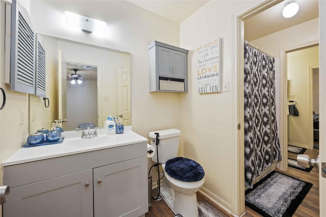 bathroom featuring wood finished floors, a shower with shower curtain, ceiling fan, toilet, and vanity