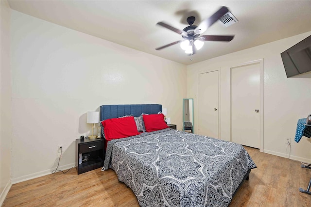 bedroom featuring wood finished floors, visible vents, a ceiling fan, and baseboards