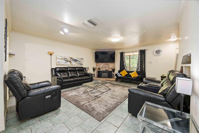 living room featuring ornamental molding, a textured ceiling, visible vents, and a brick fireplace