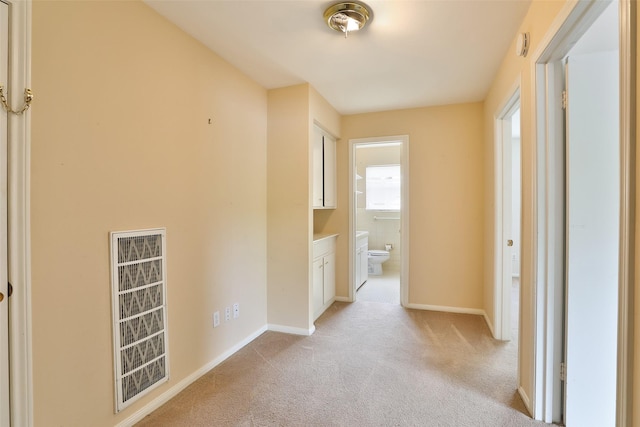 hallway featuring light carpet and baseboards