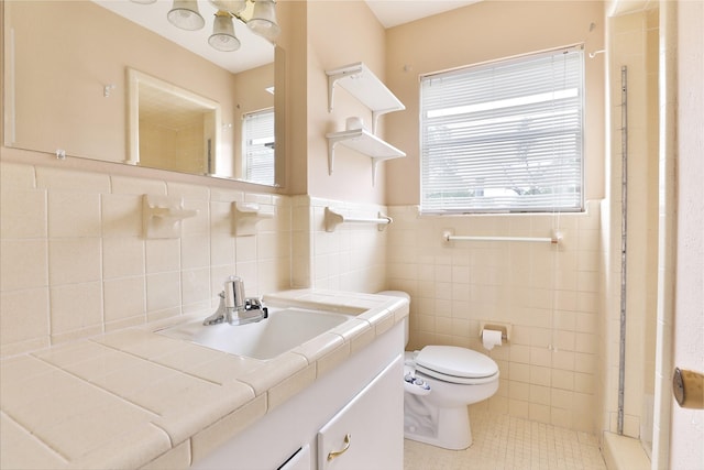 bathroom with tile patterned floors, toilet, tile walls, wainscoting, and vanity