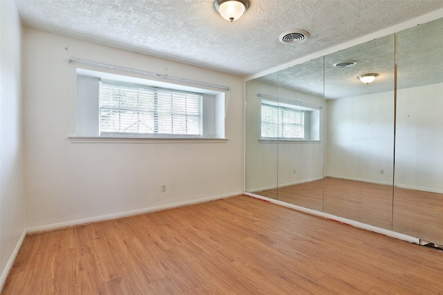 unfurnished bedroom featuring wood finished floors, visible vents, and a textured ceiling