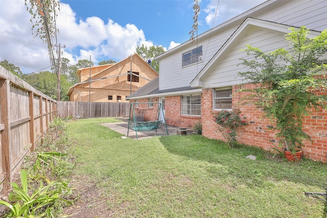 rear view of house with a fenced backyard, brick siding, a yard, and a patio