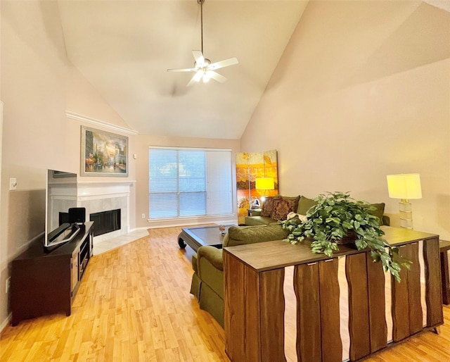 living area featuring light wood-style flooring, ceiling fan, a premium fireplace, baseboards, and high vaulted ceiling