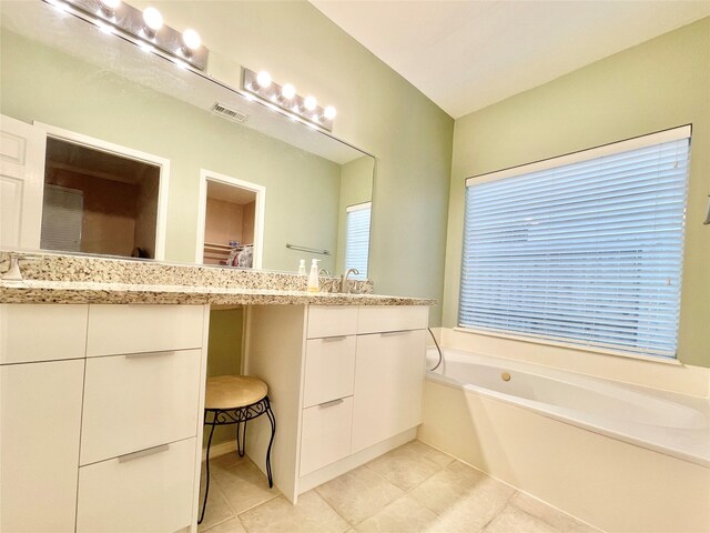 bathroom featuring visible vents, a bath, vanity, tile patterned flooring, and a walk in closet