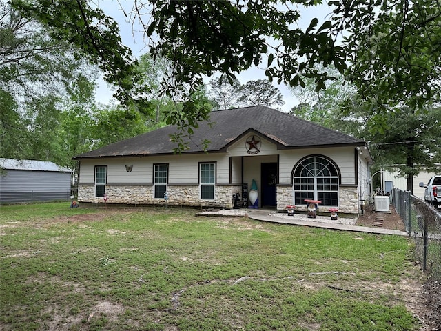 back of house with fence, a yard, and stone siding