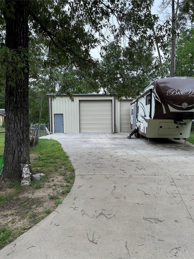 detached garage featuring fence and driveway