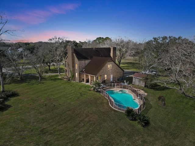 3003 Sky Ranch Dr, Alvin, TX 77511 - rear view of house with a chimney, a yard, brick siding, and a pool with connected hot tub