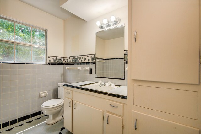 bathroom with tile patterned floors, vanity, tile walls, a wainscoted wall, and toilet