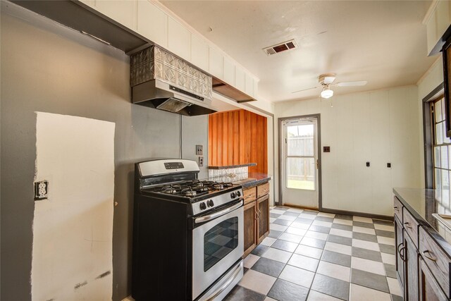 kitchen featuring stainless steel range with gas stovetop, dark countertops, visible vents, a ceiling fan, and under cabinet range hood