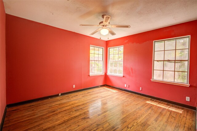 spare room featuring a textured ceiling, wood finished floors, a ceiling fan, and baseboards