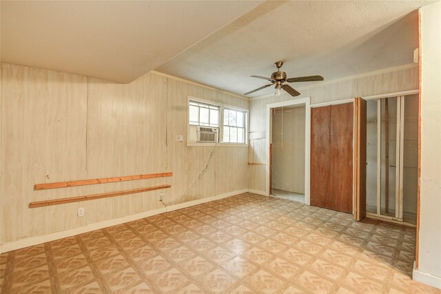 interior space featuring ceiling fan, baseboards, and wooden walls